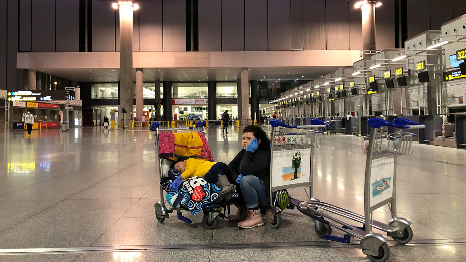Woman with her daughter wait for their charter flight to Poland, as she wear protective gloves against coronavirus (COVID-19) at the airport in Malaga, Spain March 17, 2020. REUTERS/Kacper Pempel